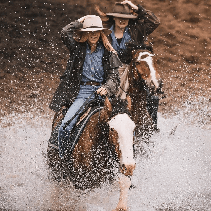 Horses and riders galloping through water