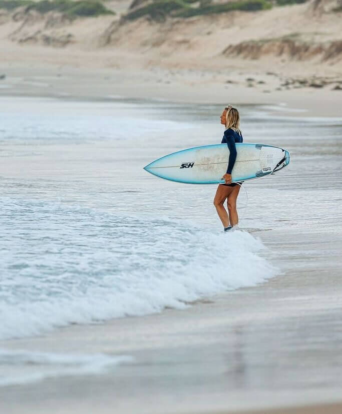 Woman surfer watching the waves before enterign the surf down at solders beach