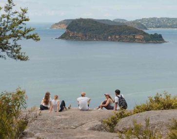 People on a clifftop overlooking Bouddi 