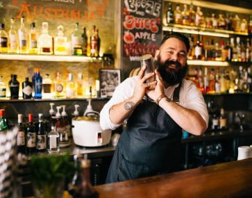 smiling man shaking cocktail in bar