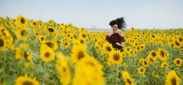 women running in sunflower field