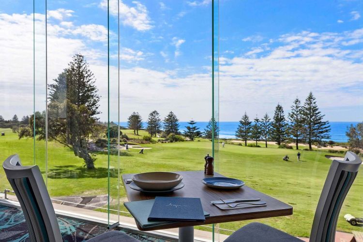 Window view of a lush green golf course backing onto a beach