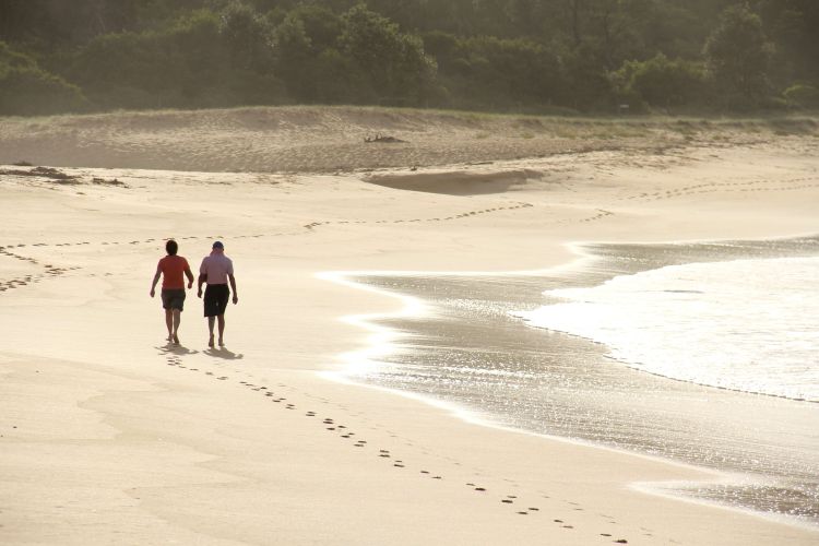 Two people walking on a calm secluded beach