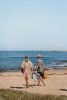 couple walking onto beach with hats and beach bags