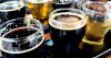 A paddle of different coloured beers in small glasses, including light beers and darker beers.