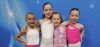 Four girls wearing pink and white with their arms around each other.