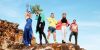 group of people celebrating diversity on coastal rockface