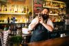 smiling man shaking cocktail in bar